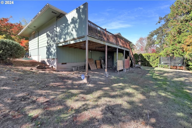 back of property featuring a trampoline and a wooden deck