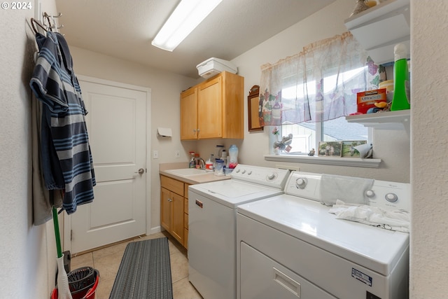 washroom with a sink, cabinet space, light tile patterned flooring, and washer and dryer