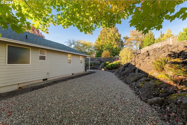 view of home's exterior featuring fence, a shingled roof, and crawl space