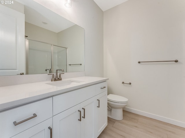 bathroom featuring vanity, hardwood / wood-style flooring, toilet, and a shower with shower door