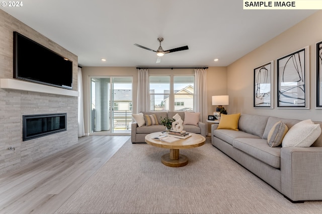 living room featuring a fireplace, light wood-type flooring, and ceiling fan