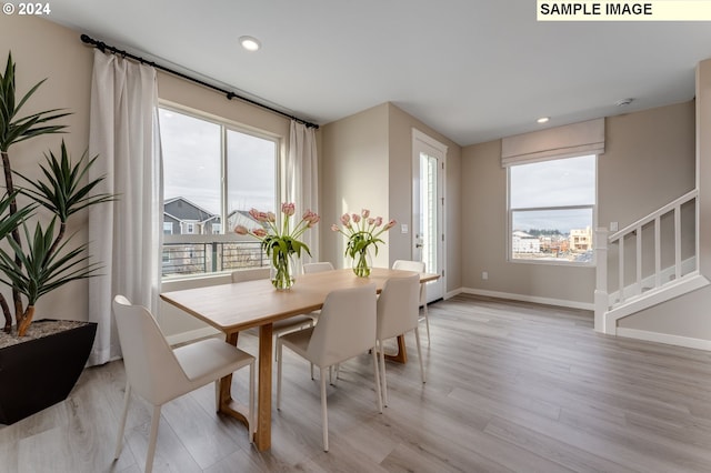 dining area with light wood-style flooring, stairs, and a wealth of natural light
