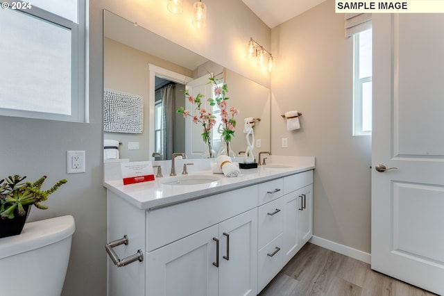 full bath featuring double vanity, a sink, wood finished floors, and toilet