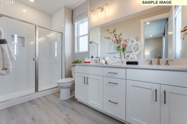 bathroom with hardwood / wood-style floors, vanity, toilet, and a shower with door