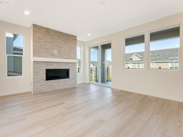 unfurnished living room with a large fireplace and light hardwood / wood-style floors