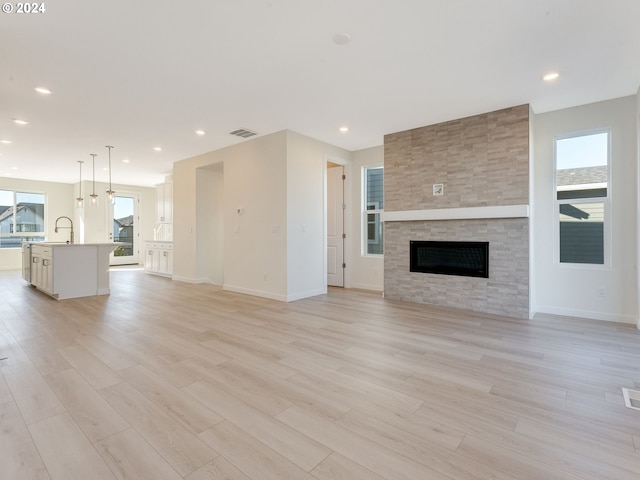 unfurnished living room featuring a fireplace, a wealth of natural light, and light hardwood / wood-style flooring