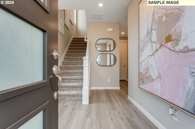 entryway with light wood-style floors, baseboards, recessed lighting, and stairs