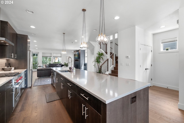 kitchen with a large island, sink, decorative light fixtures, and light hardwood / wood-style flooring