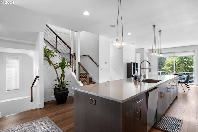 kitchen featuring stainless steel dishwasher, dark brown cabinetry, a kitchen island with sink, dark wood-type flooring, and sink