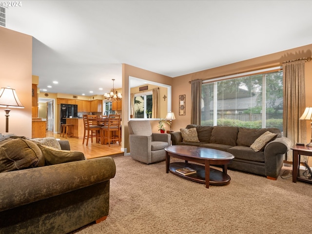 living room featuring light carpet and a notable chandelier