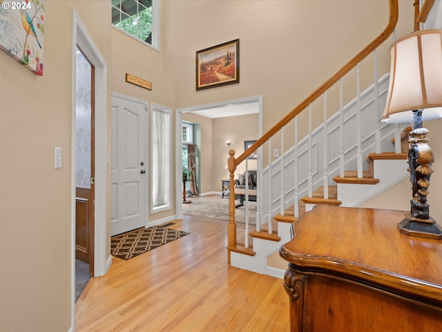 foyer entrance with a towering ceiling and light hardwood / wood-style flooring