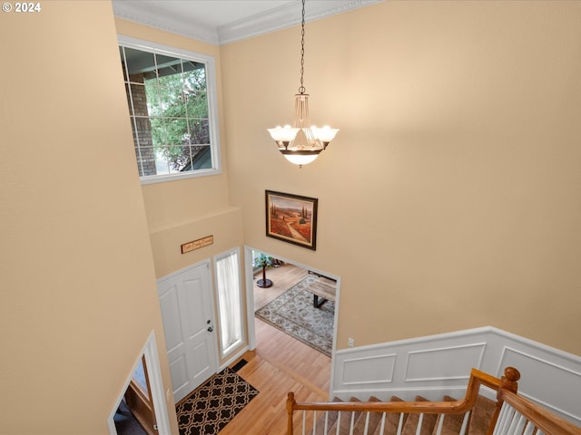 entryway featuring a notable chandelier, ornamental molding, light hardwood / wood-style flooring, and a high ceiling