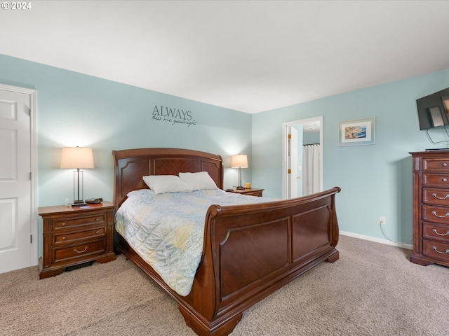 bedroom with ensuite bathroom and light colored carpet