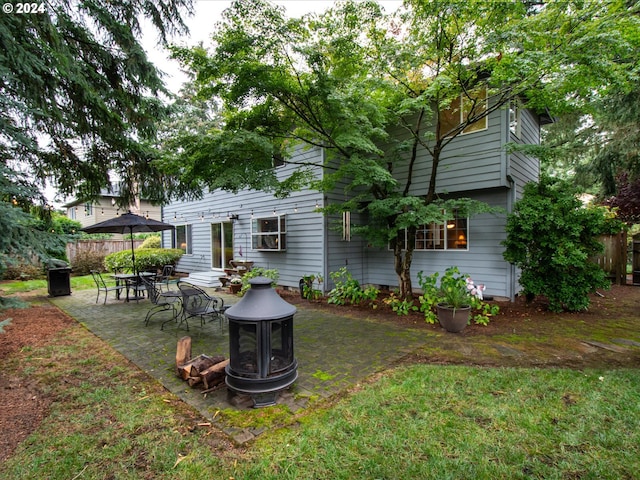 back of house with an outdoor fire pit, a patio area, and a lawn