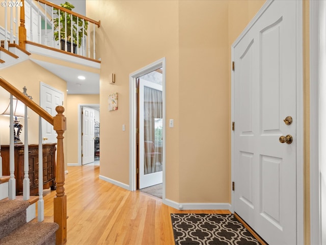 entryway featuring light hardwood / wood-style floors and a towering ceiling