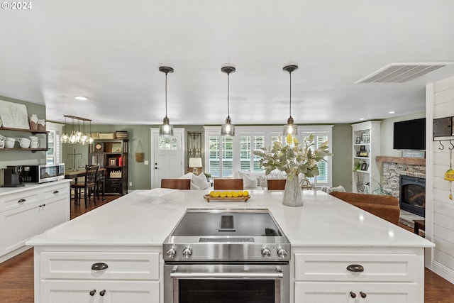 kitchen with appliances with stainless steel finishes, a kitchen island, light stone counters, and a stone fireplace