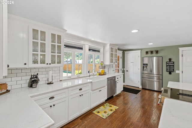 kitchen featuring white cabinetry, dark hardwood / wood-style flooring, light stone counters, sink, and appliances with stainless steel finishes