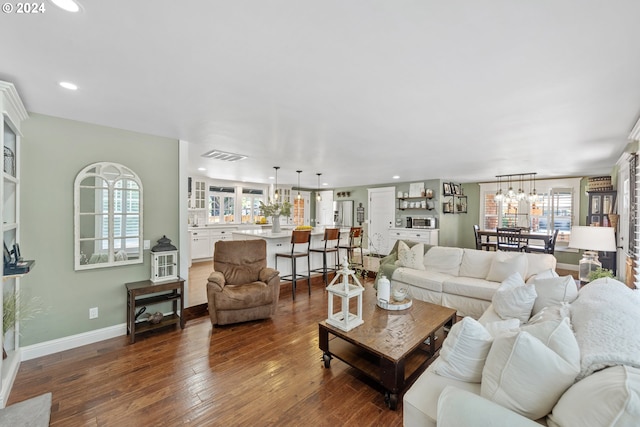 living room featuring plenty of natural light, dark hardwood / wood-style floors, and a notable chandelier