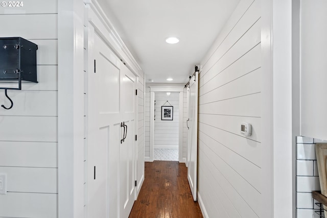 hall featuring a barn door and dark wood-type flooring