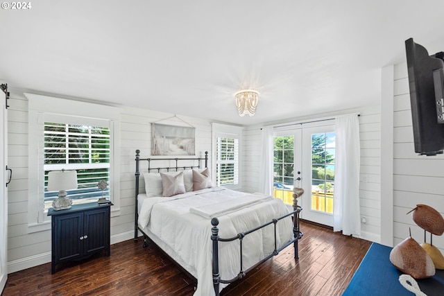 bedroom featuring dark wood-type flooring, multiple windows, wooden walls, and access to exterior