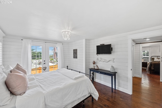 bedroom featuring wooden walls, dark hardwood / wood-style floors, access to outside, and french doors