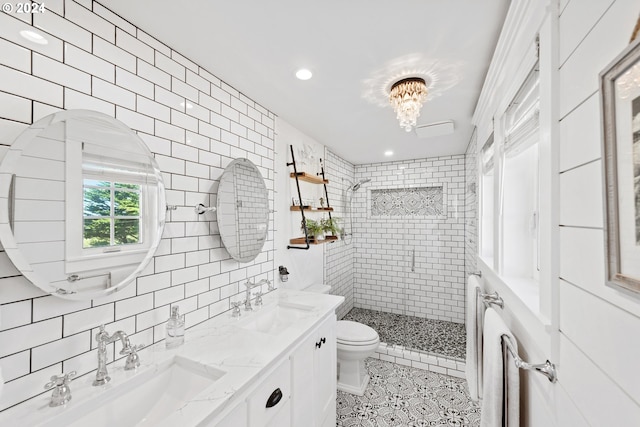 bathroom featuring tile patterned flooring, toilet, a tile shower, tile walls, and vanity