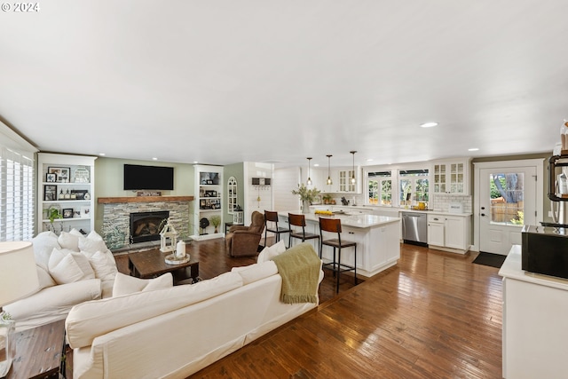 living room with dark wood-type flooring and a stone fireplace