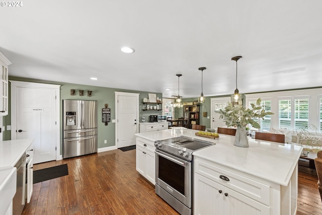 kitchen featuring hanging light fixtures, stainless steel appliances, white cabinetry, dark hardwood / wood-style floors, and a kitchen island