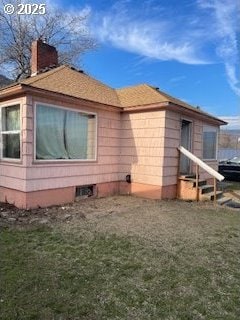 view of side of home featuring a chimney and a yard