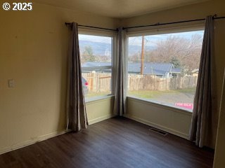 3214 W 10th St, The Dalles, OR 97058 - unfurnished room with visible vents, baseboards, and dark wood-type flooring