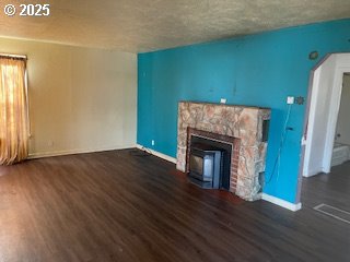 3214 W 10th St, The Dalles, OR 97058 - unfurnished living room featuring a textured ceiling, dark wood-style flooring, and a fireplace