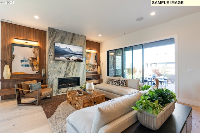 living room with recessed lighting, light wood-style floors, visible vents, and a high end fireplace