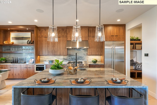 kitchen with modern cabinets, a center island with sink, ventilation hood, appliances with stainless steel finishes, and brown cabinetry