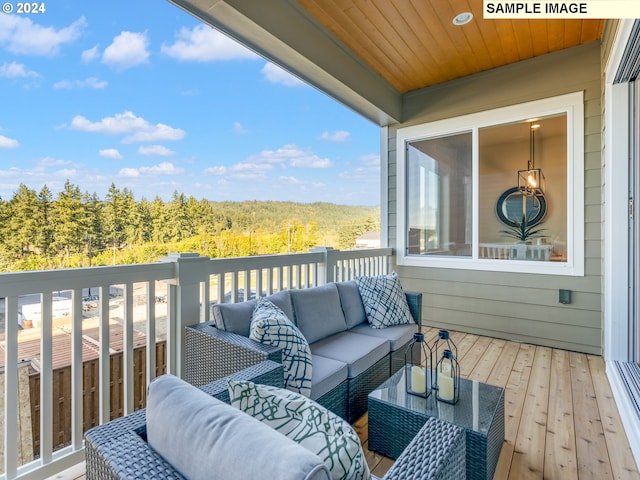 balcony with an outdoor hangout area and a wooded view