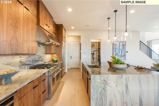 kitchen with light stone countertops, under cabinet range hood, double oven range, modern cabinets, and a sink