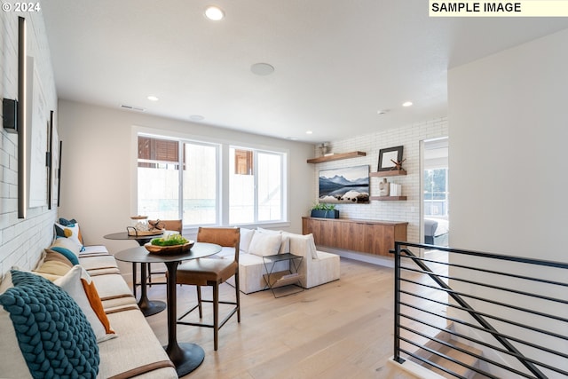 living room featuring brick wall, a healthy amount of sunlight, and light hardwood / wood-style floors