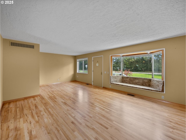 unfurnished living room featuring wood finished floors, a textured ceiling, and baseboards