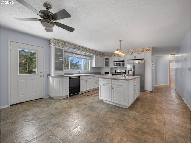 kitchen with appliances with stainless steel finishes, glass insert cabinets, a sink, a textured ceiling, and baseboards