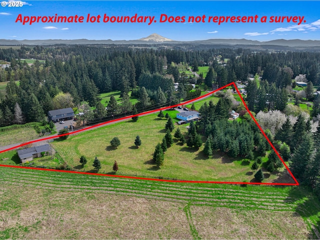 view of rural area with mountains, a heavily wooded area, and property boundaries highlighted