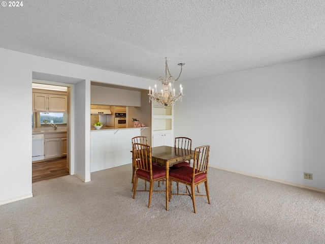 carpeted dining area with a textured ceiling, baseboards, a sink, and a chandelier