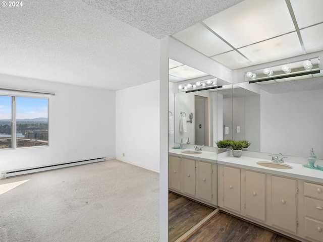 full bath featuring double vanity, a baseboard radiator, a textured ceiling, and a sink