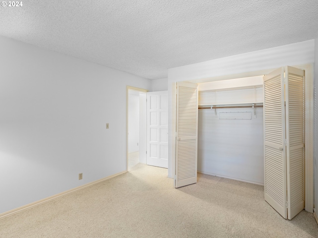 unfurnished bedroom featuring carpet floors, a textured ceiling, baseboards, and a closet