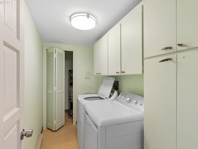 laundry area featuring a textured ceiling, light floors, washing machine and dryer, and cabinet space