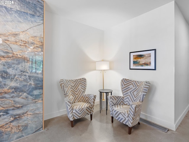 living area with concrete flooring and baseboards