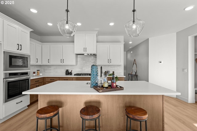 kitchen featuring white cabinets, a center island, a kitchen bar, and appliances with stainless steel finishes