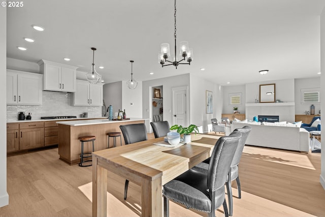 dining space with a chandelier, light hardwood / wood-style floors, and a fireplace