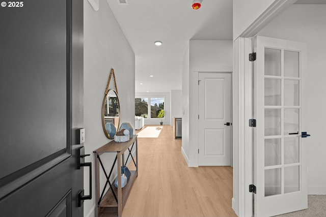 hallway with french doors and light hardwood / wood-style flooring