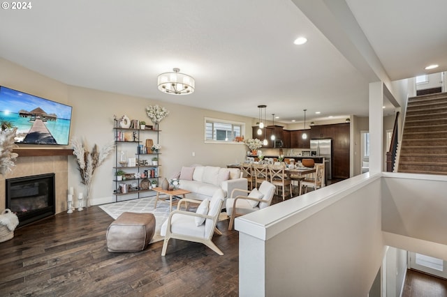 living room with a tiled fireplace and dark wood-type flooring