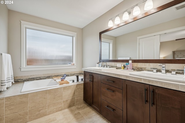 bathroom with vanity and tiled tub