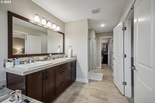 bathroom with vanity, a textured ceiling, and walk in shower